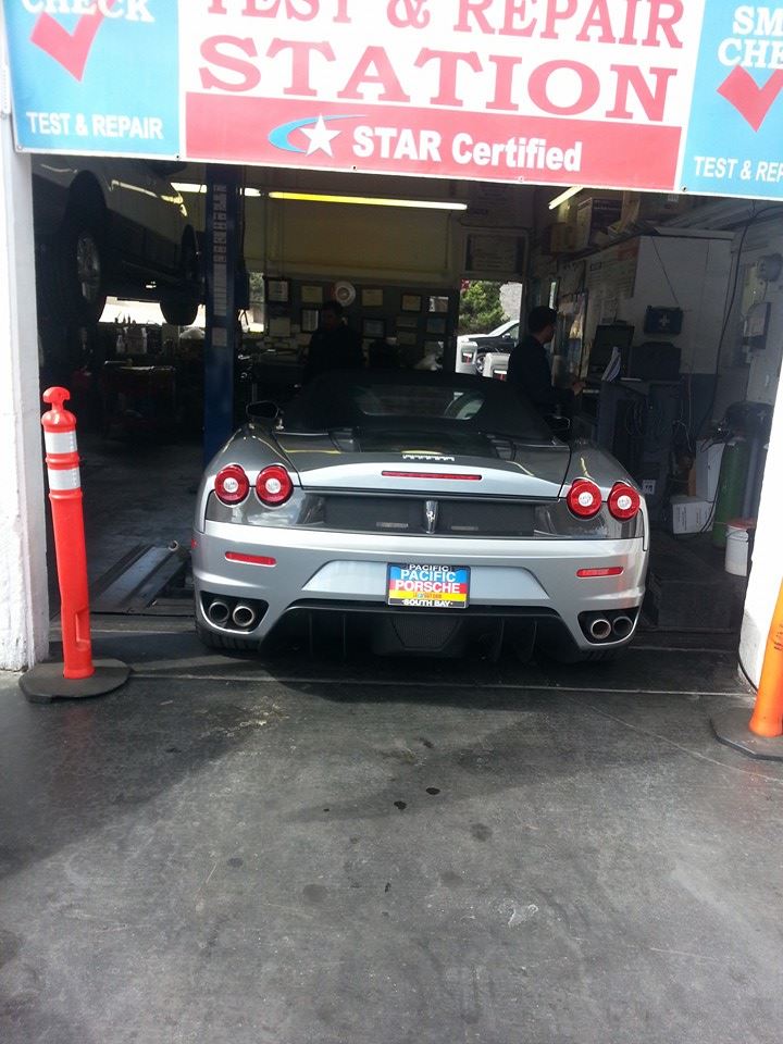 A Ferrari F430 in the bay at Nery's Auto Repair beneath the smog test and repair banner