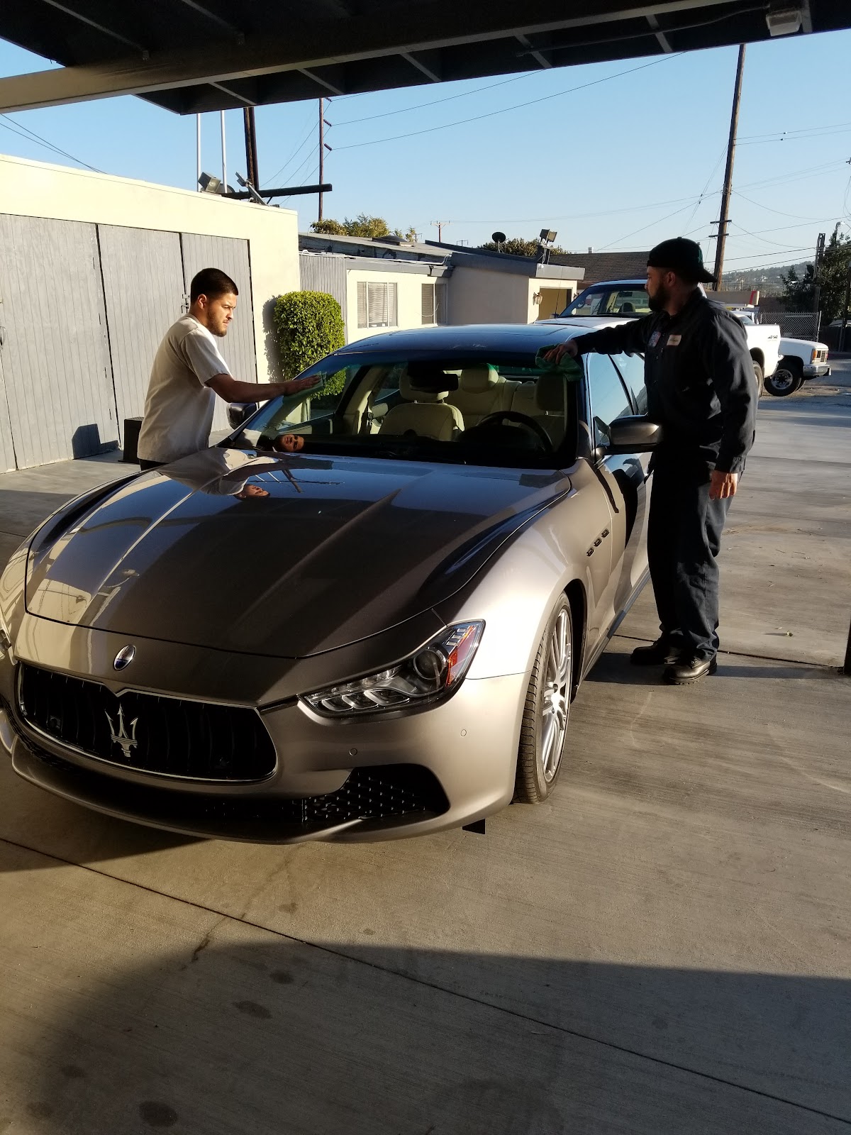 Two members of the team at Nery's Auto Repair alongside a Maserati Ghibli on the forecourt